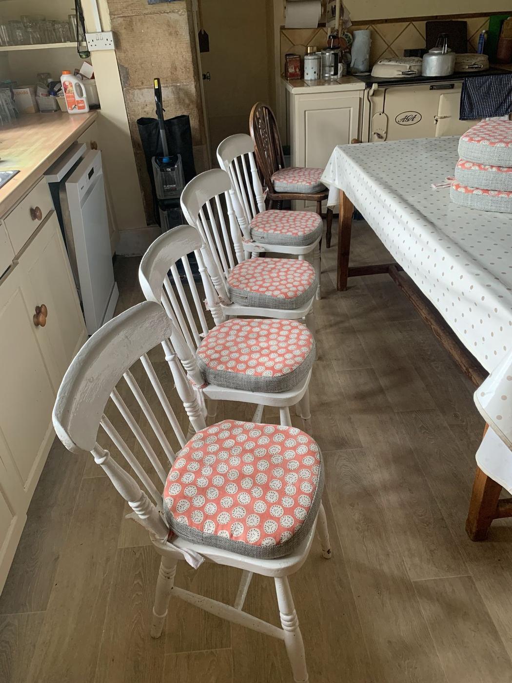 White spindle-back kitchen chairs with new coral seat pads, back in the kitchen