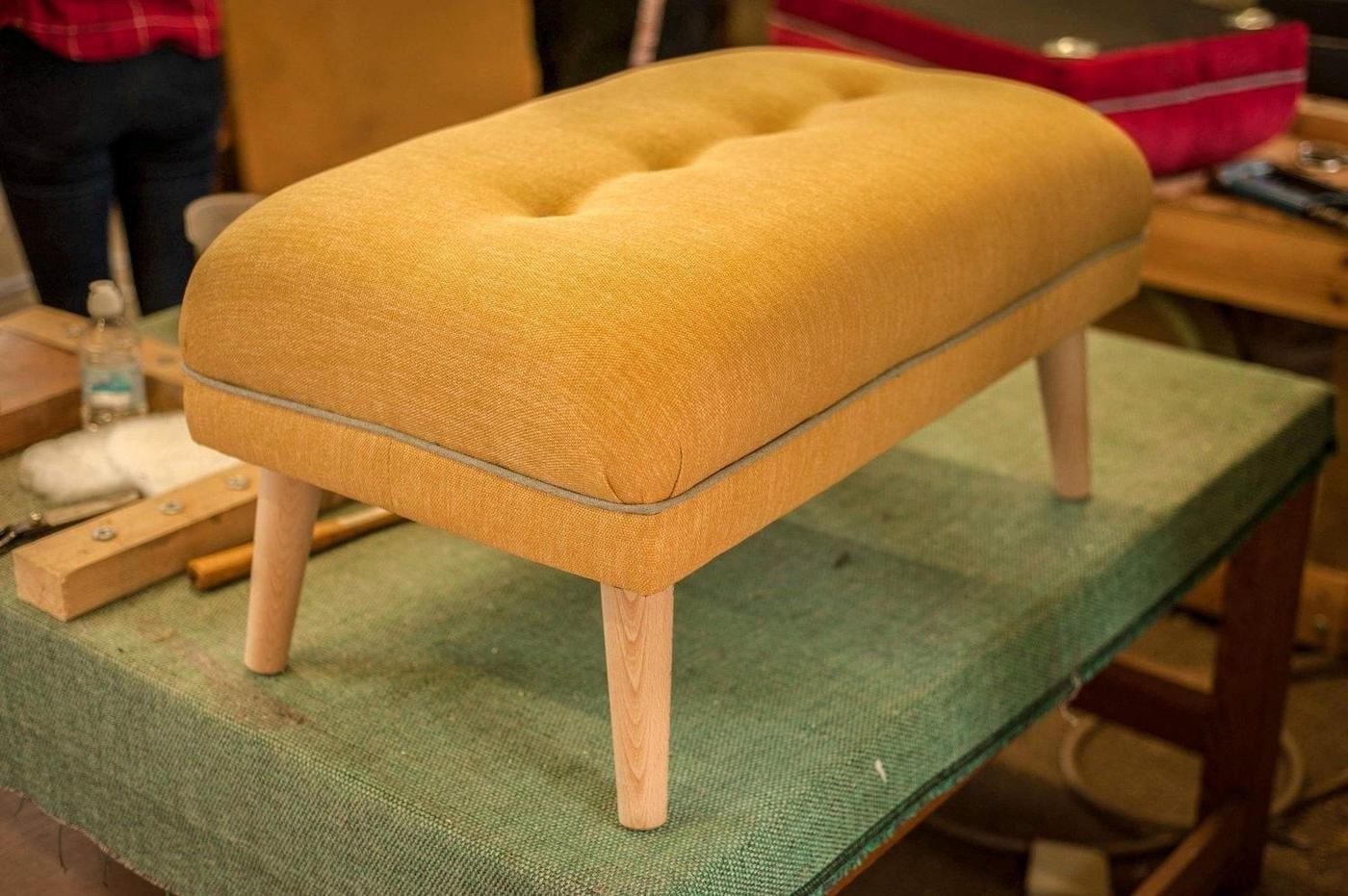 A buttoned ochre footstool made in a class