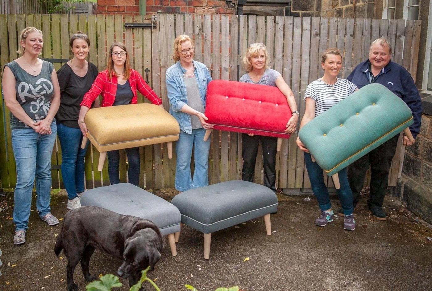 A class group in the yard holding the footstools and seat pads they made, with a dog