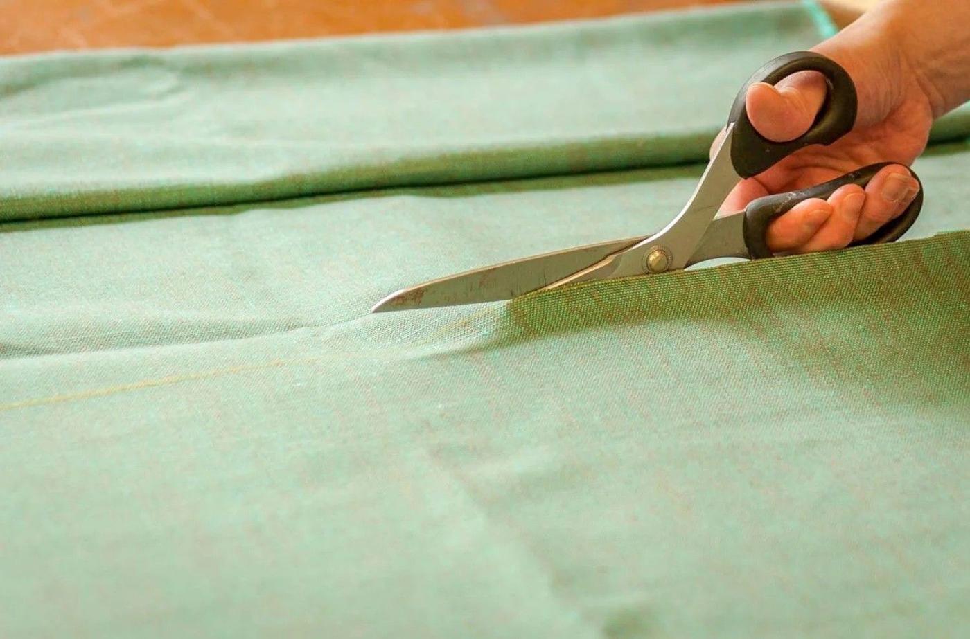 Shears cutting a length of sage green fabric