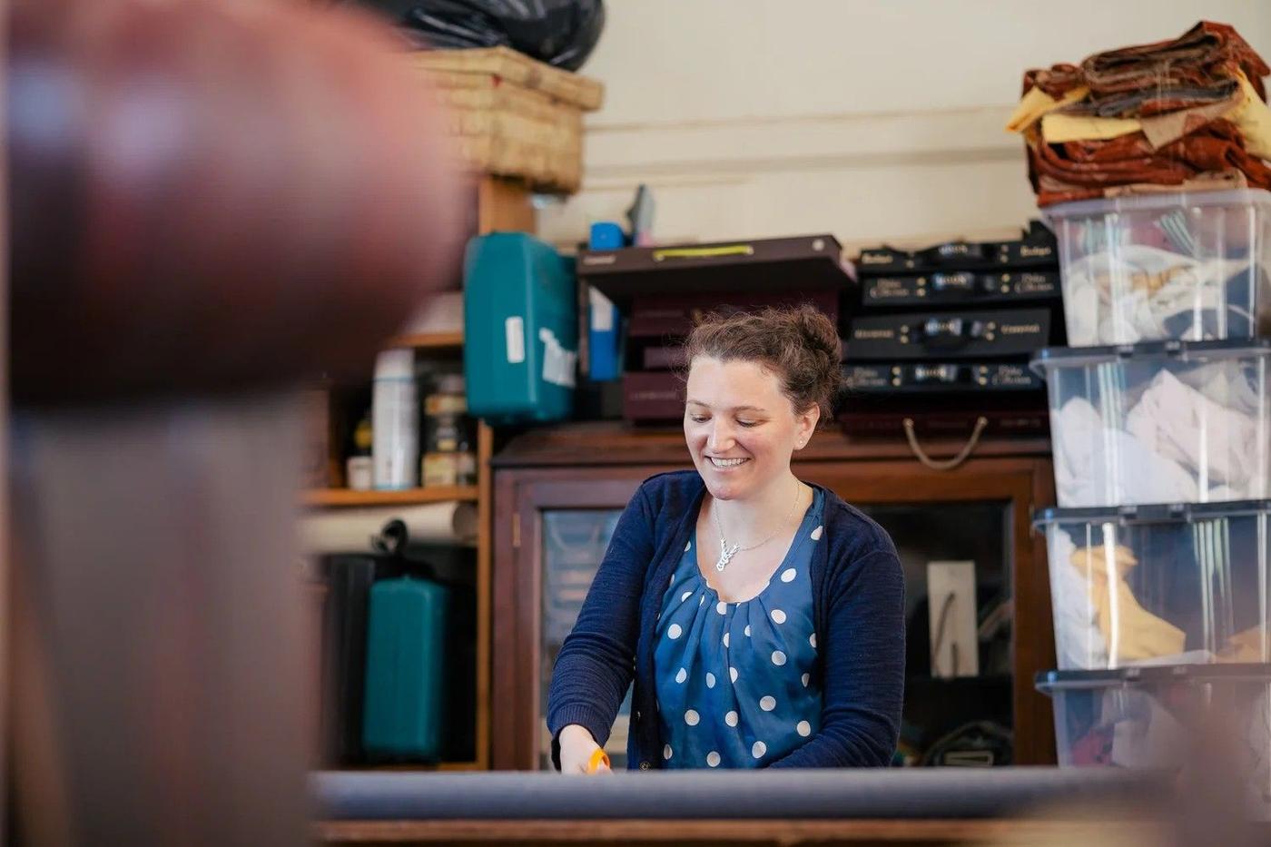 Emily at her workbench in the studio, surrounded by fabric rolls