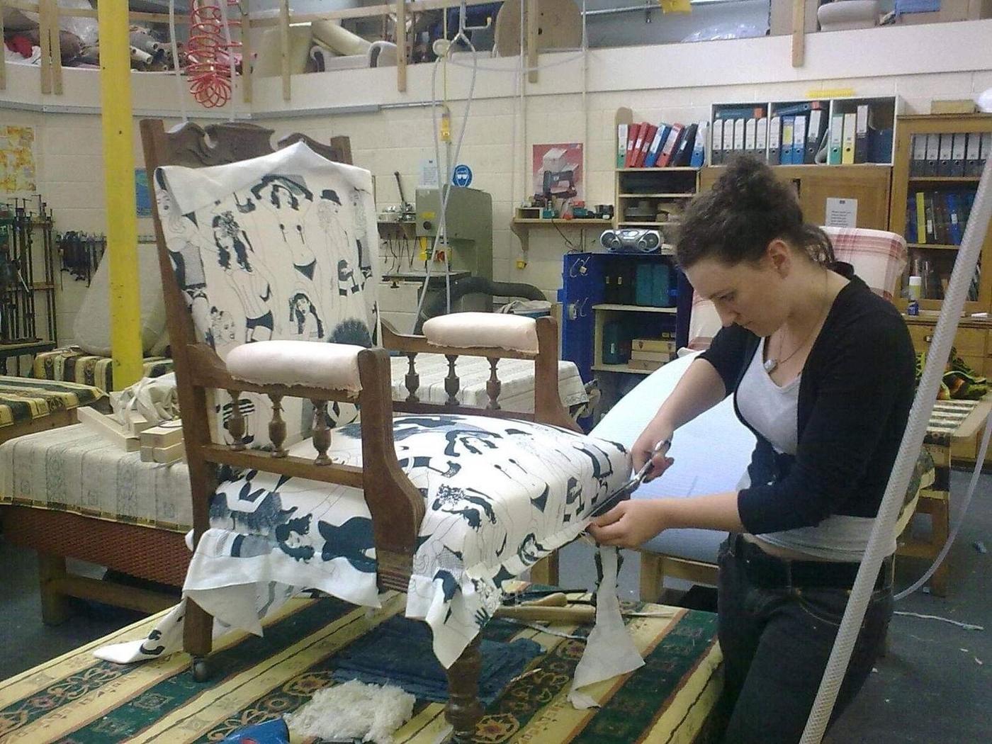 Emily cutting and fitting a black and white print on an armchair in the workshop