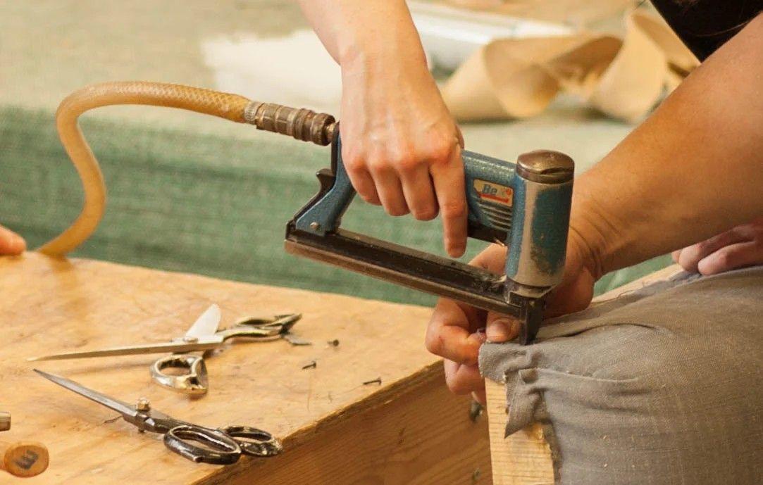 Staple gun fixing fabric to a frame