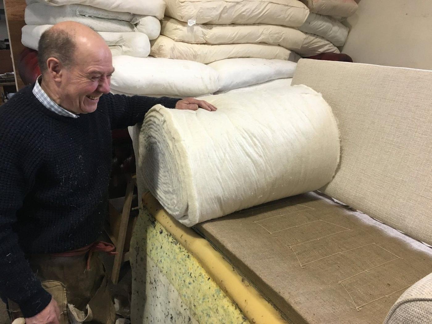 A roll of wadding being laid over a seat in the workshop